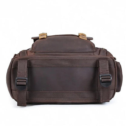 Dark brown leather camera backpack rear view with wide strap and metal buckle accents