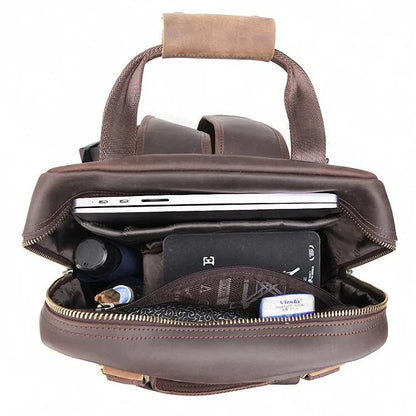 Brown leather camera backpack open at top, showing padded camera compartments and zipper closure