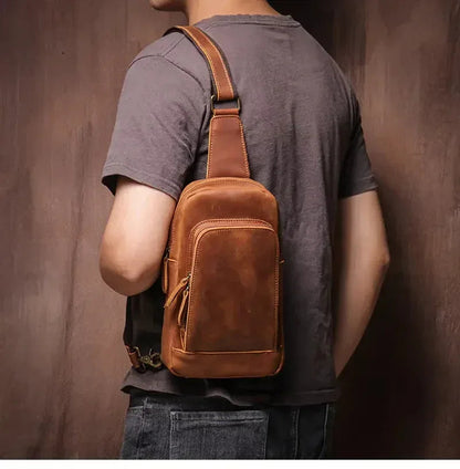 Brown leather crossbody sling bag worn by person, front view with adjustable strap