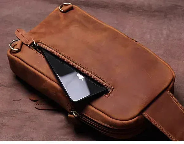 Brown leather crossbody pack with front zip, holds a phone in an exterior slot