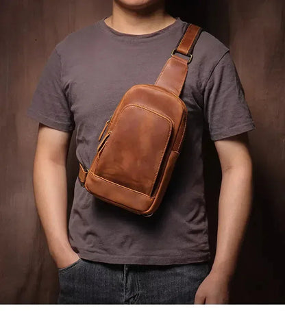 Brown leather crossbody sling bag worn across chest with front zipper pocket