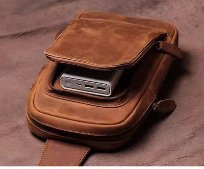 Brown leather crossbody bag with flap open showing a phone compartment pocket