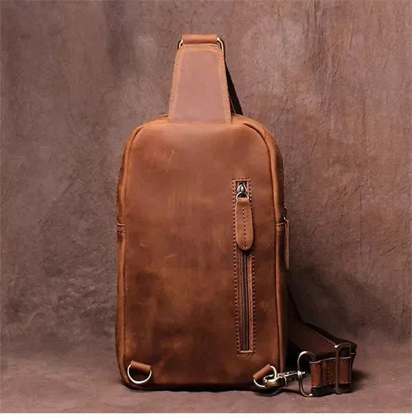 Brown leather crossbody pack with front zip and top strap, metal hardware accents