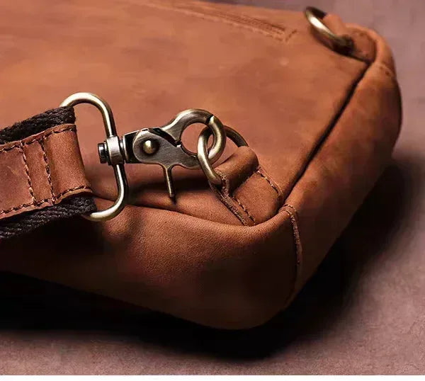 Brown leather crossbody pack close-up of strap rings and zipper pull hardware