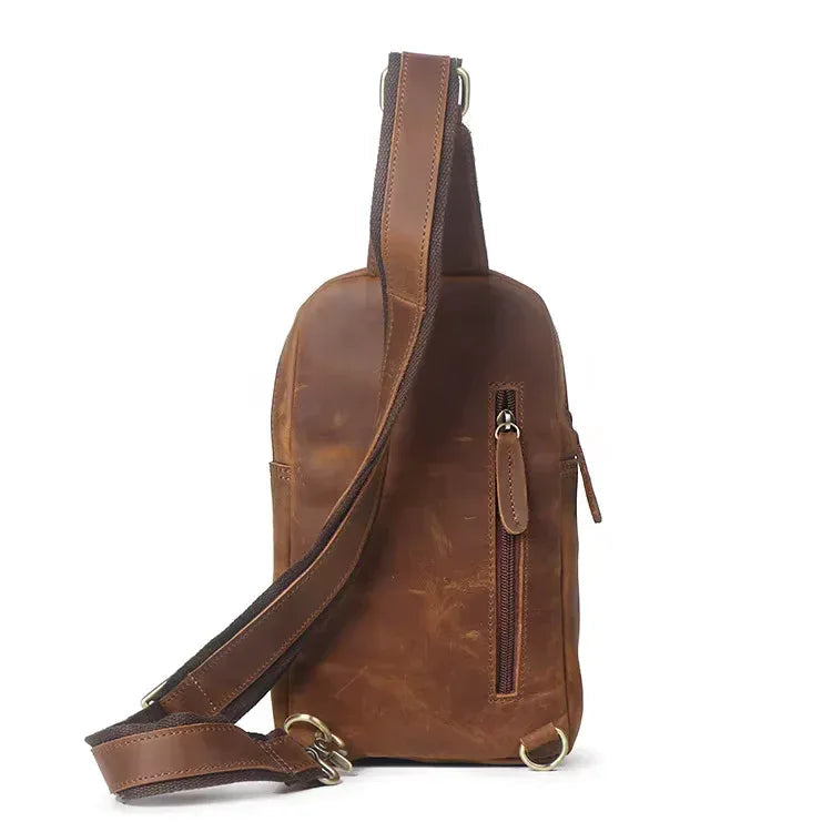 Brown leather crossbody sling bag angled view with zipper pocket and shoulder strap