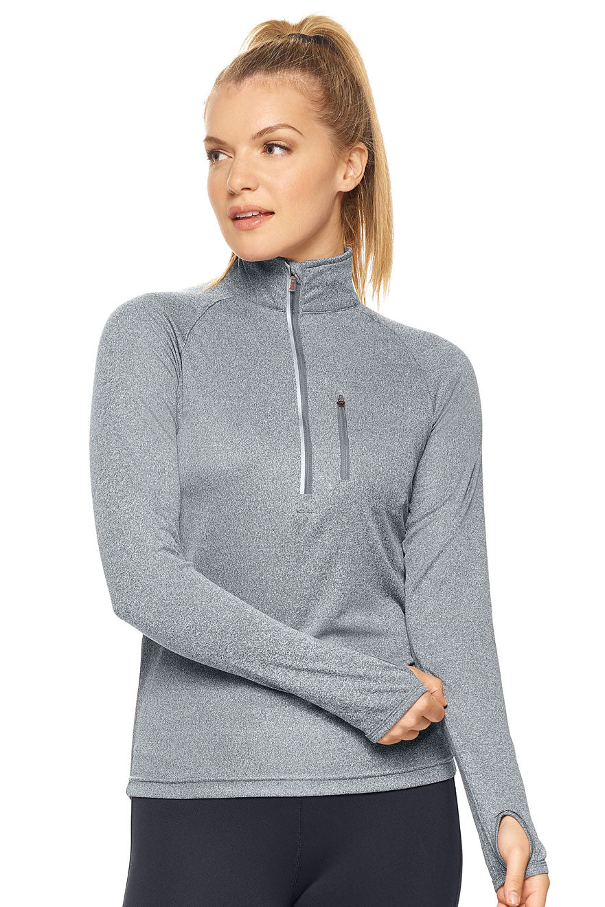 Woman wearing a gray long-sleeve athletic top with a quarter zip on a white background