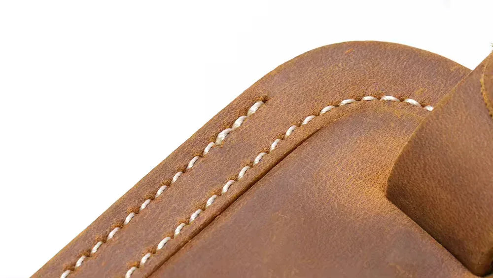 Close-up of full grain leather luggage tag stitching and curved edge detail.