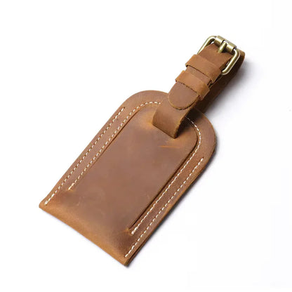 Tan full grain leather luggage tag with metal buckle strap and stitched border.