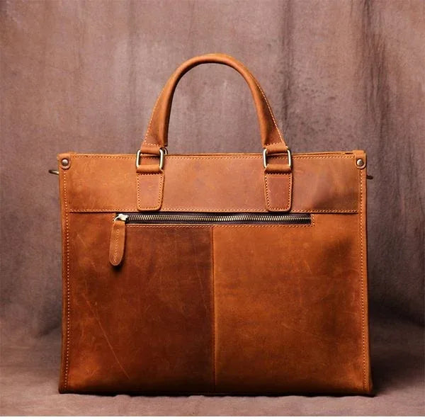 Brown leather messenger bag with zippered front pocket and top carry handles