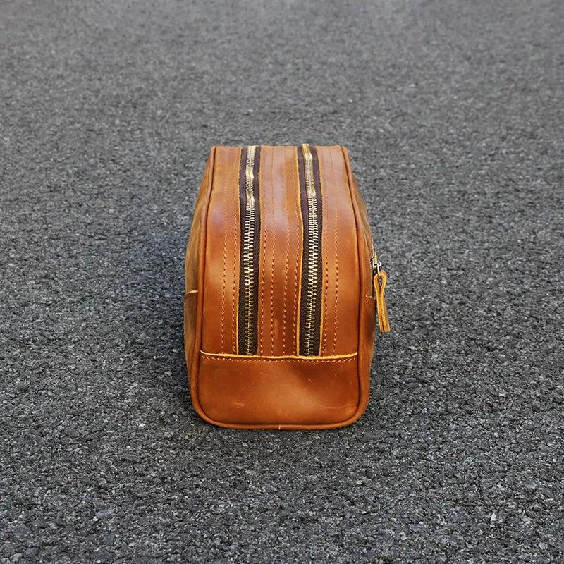 Brown leather toiletry bag front view; vertical zip seams and base panel