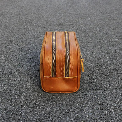 Brown leather toiletry bag front view; vertical zip seams and base panel