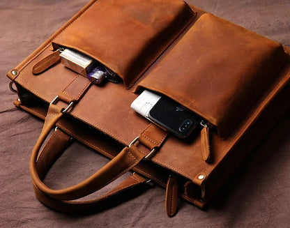 Brown leather messenger bag open flap showing interior sleeves and front buckle straps