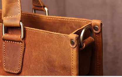 Brown leather messenger bag top handle with metal grommets on side panel