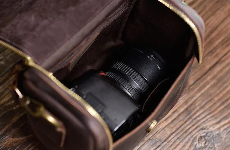 Small leather camera bag interior with lens compartment and zipper track detail.