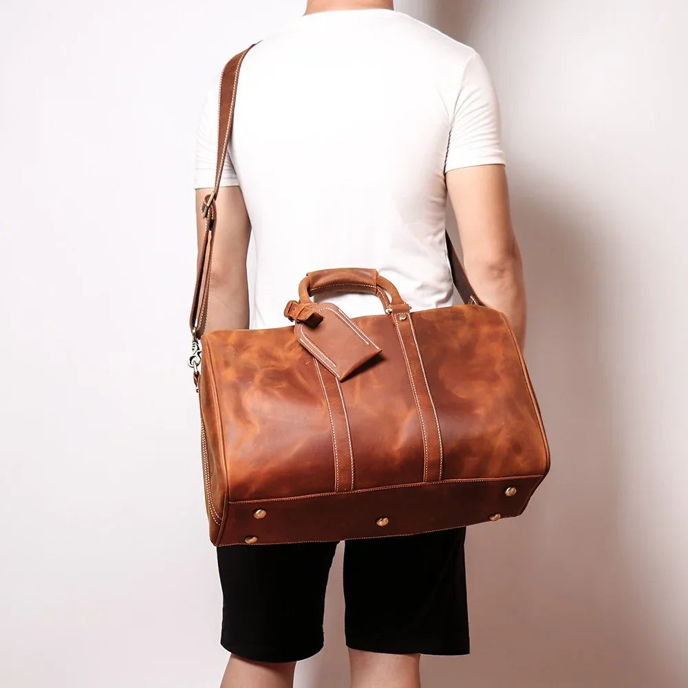 Small leather duffle bag in brown, rear view with handles and strap hardware