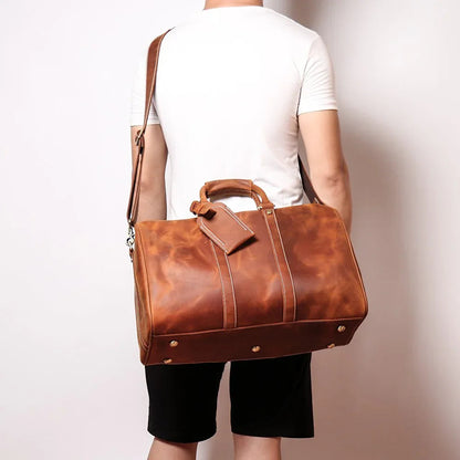 Small leather duffle bag in brown, rear view with handles and strap hardware