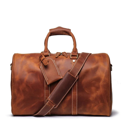 Small leather duffle bag in brown with top handles, crossbody strap, and zip front
