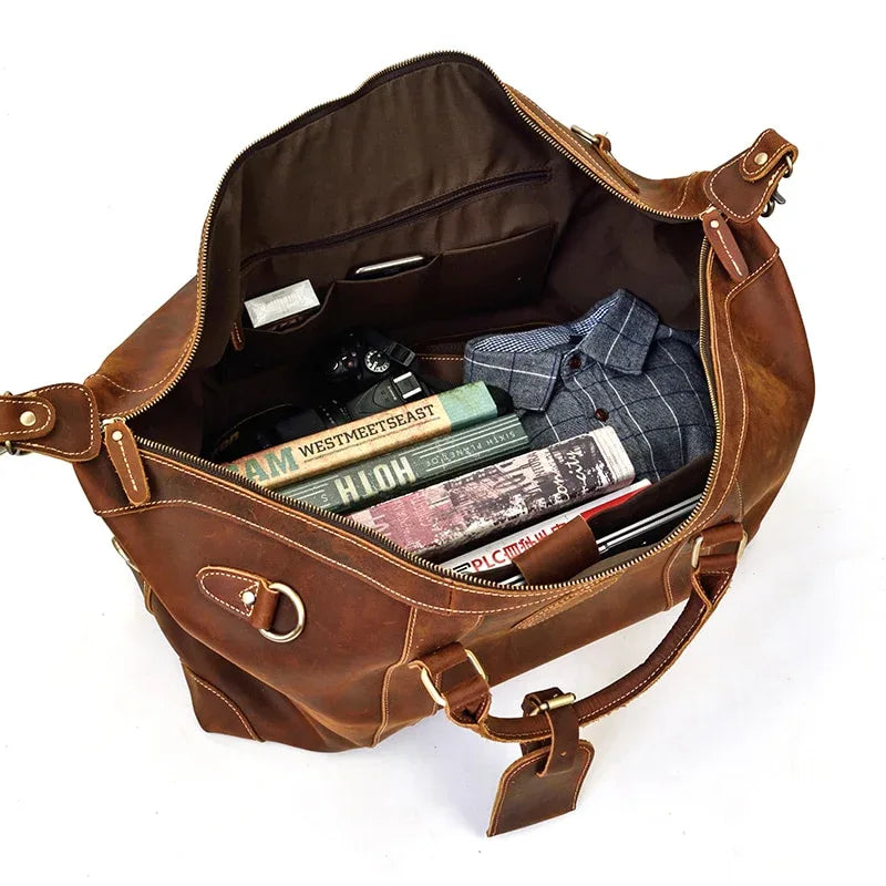 Brown leather duffle bag open showing interior lining and small zipper pocket
