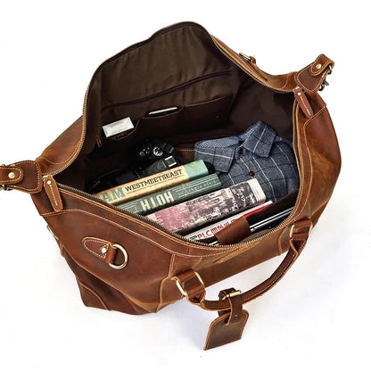 Brown leather duffle bag open showing interior lining and small zipper pocket