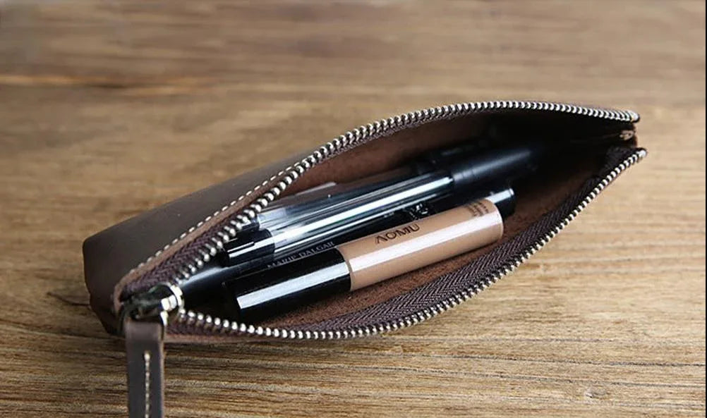 Brown leather pencil case open with pens inside and silver zipper hardware