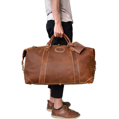 Vintage leather duffle bag carried by hand, brown color, with detachable strap.