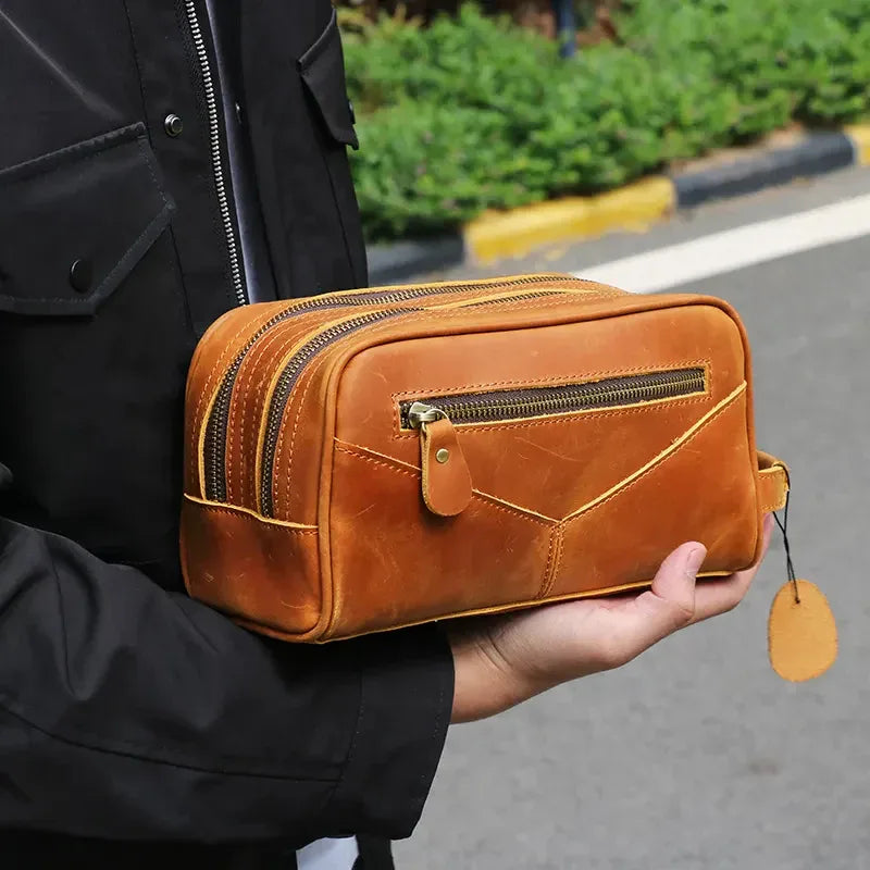 Small tan leather toiletry bag with front zip pocket and metal zipper pull