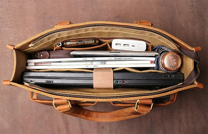 Brown leather messenger bag interior with notebooks and devices in a zippered compartment