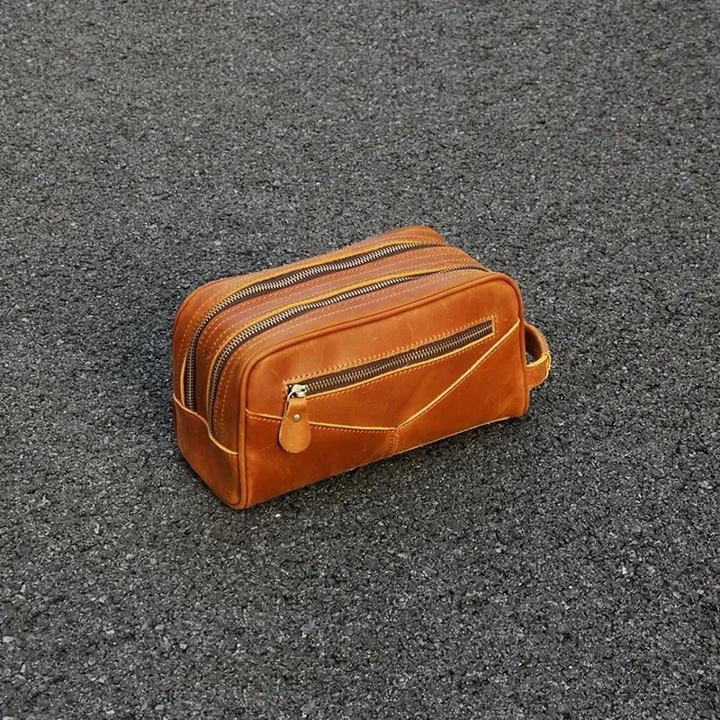 Brown leather toiletry bag with zip-top closure and side strap