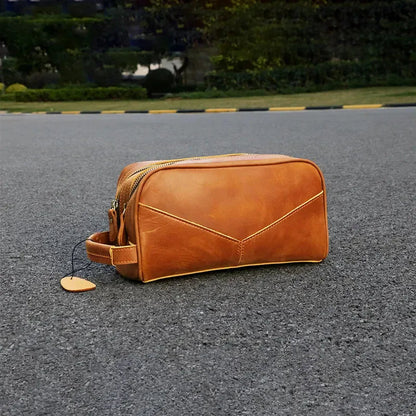 Tan leather travel toiletry bag with double zippers and side carry handle