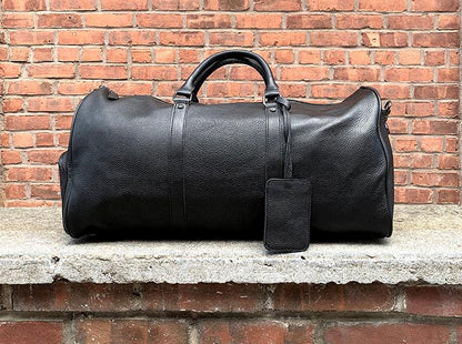 Black vintage leather weekender duffle bag with front zipper and hanging luggage tag