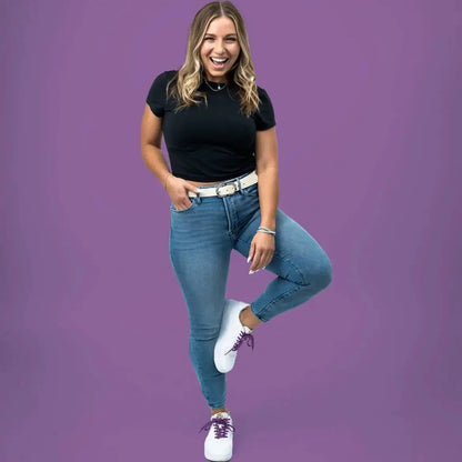 Woman wearing a black top and blue jeans on a purple background