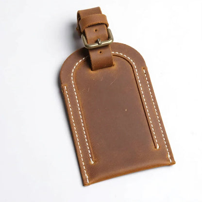 Brown full-grain leather luggage tag with buckle strap and stitched edges