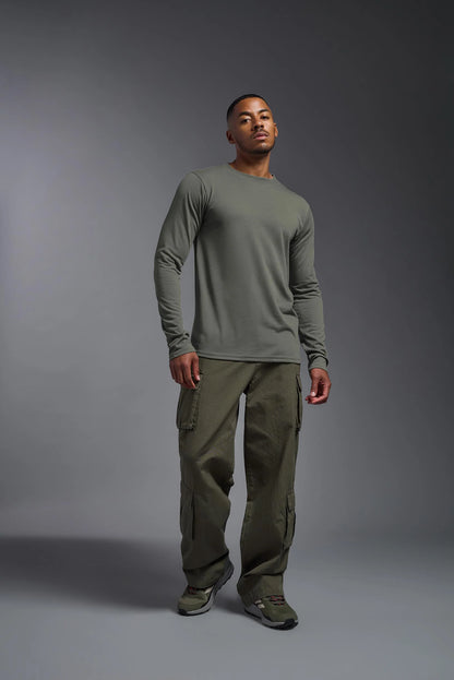 Man wearing a green long-sleeve shirt and cargo pants on a gray background