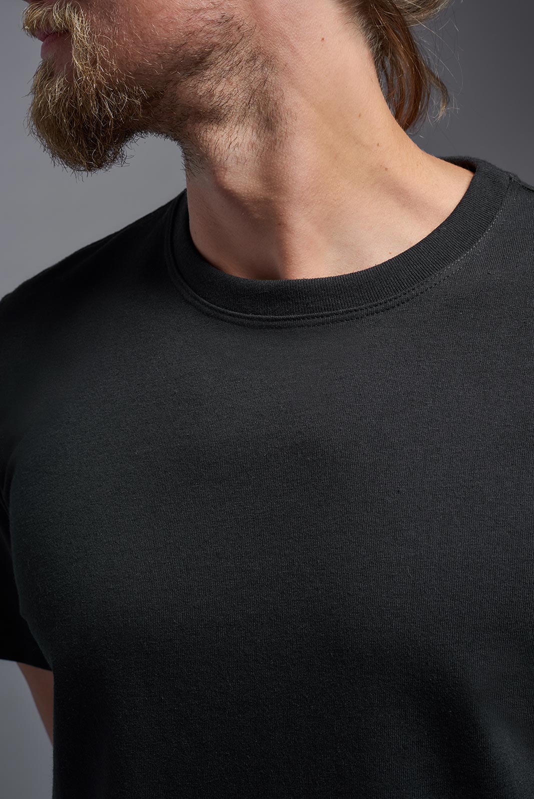 Close-up of a person wearing a black t-shirt against a gray background