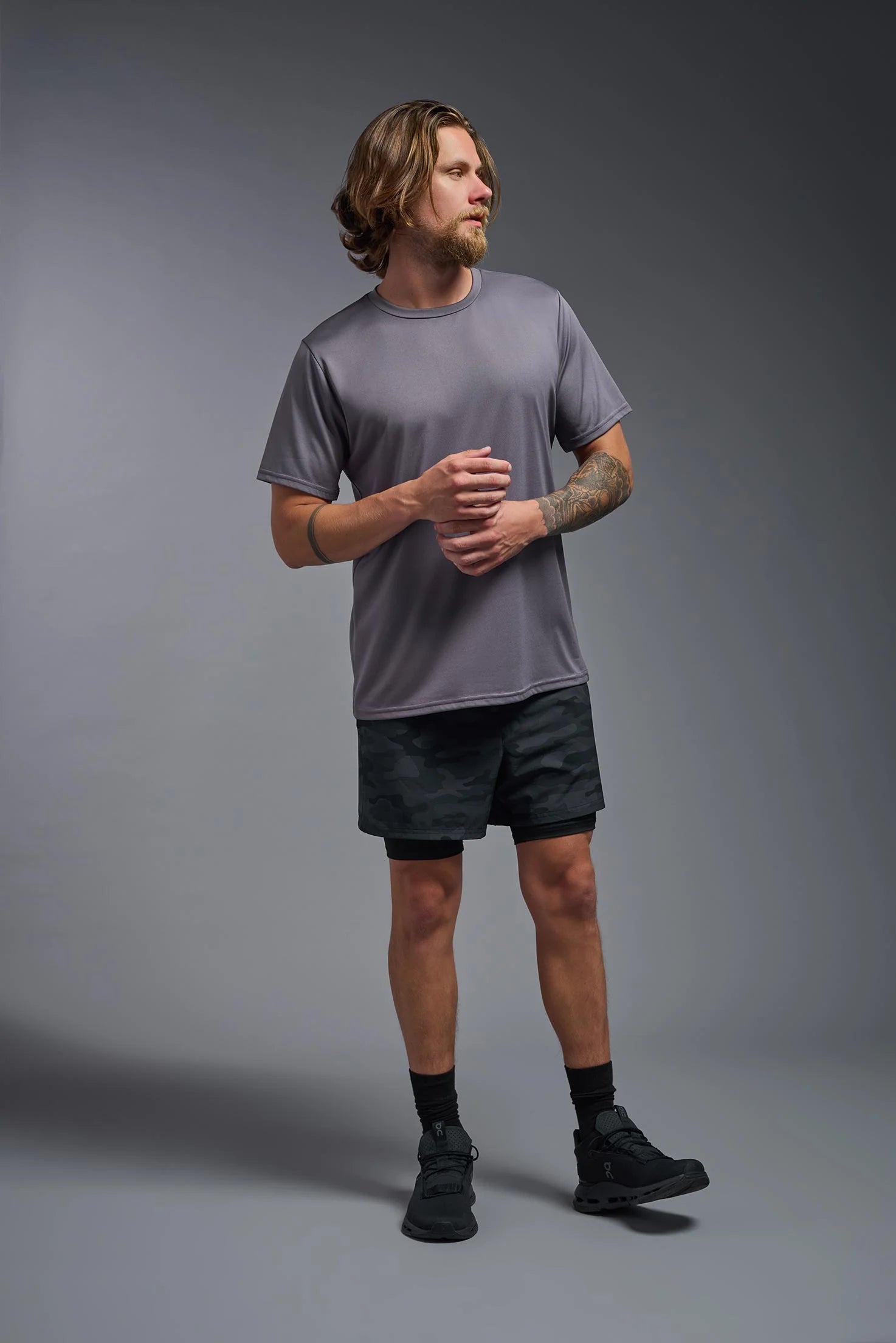 Man wearing a gray t-shirt and black shorts on a gray background