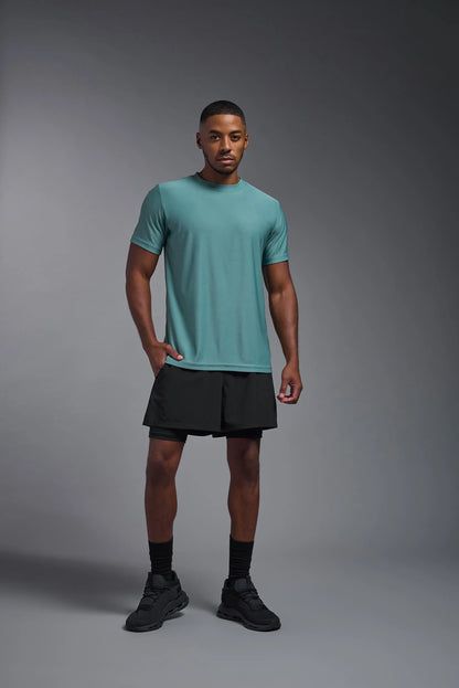 Man wearing a teal t-shirt and black shorts on a gray background