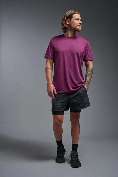 Man wearing a purple t-shirt and black shorts on a gray background