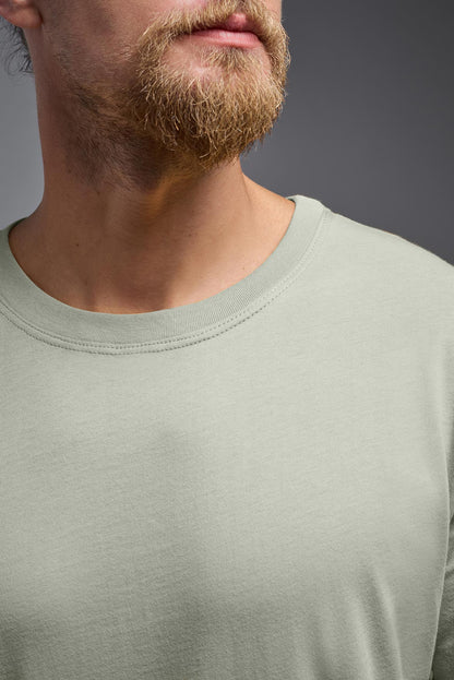 Close-up of a person wearing a light green long-sleeve shirt against a gray background