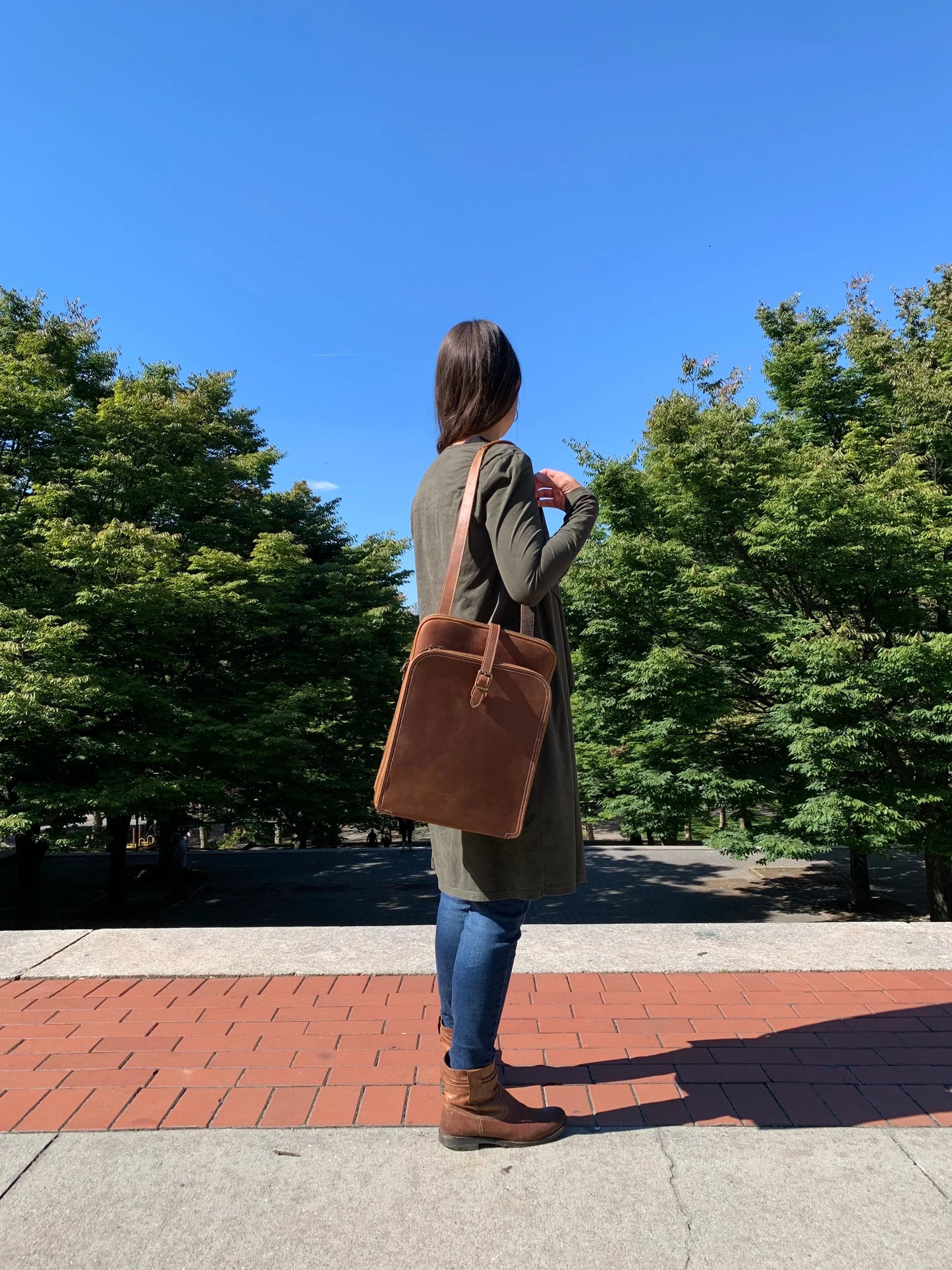 Small leather backpack on model, side view with top handle and straps