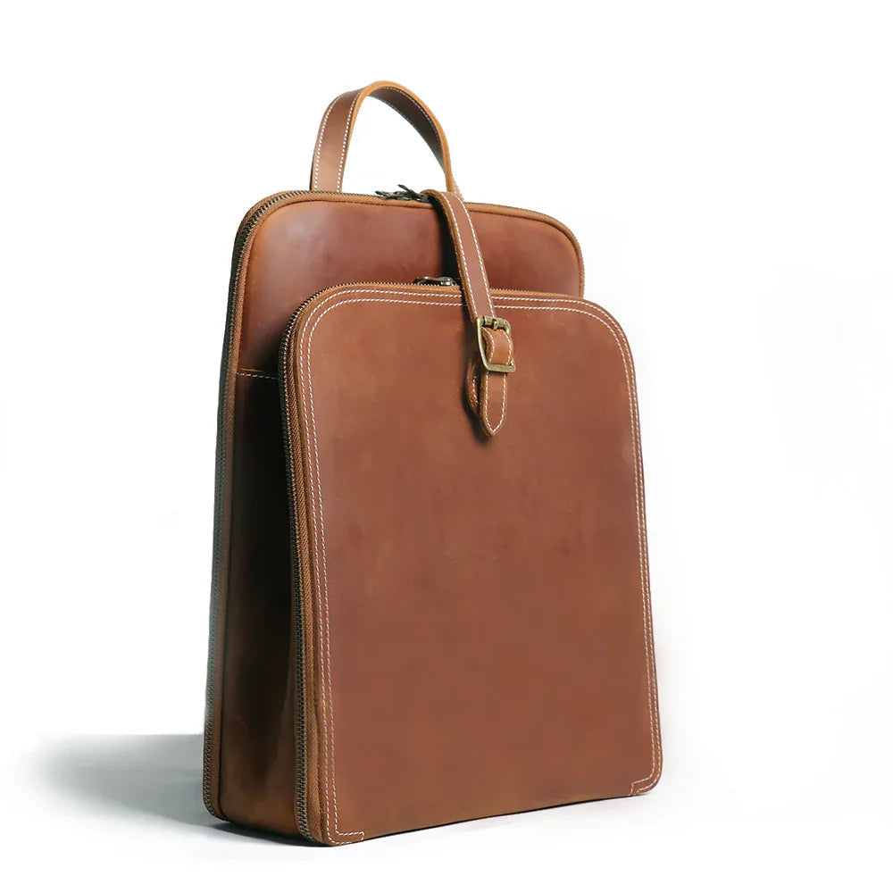 Small brown leather backpack with arched top handle and front buckle closure