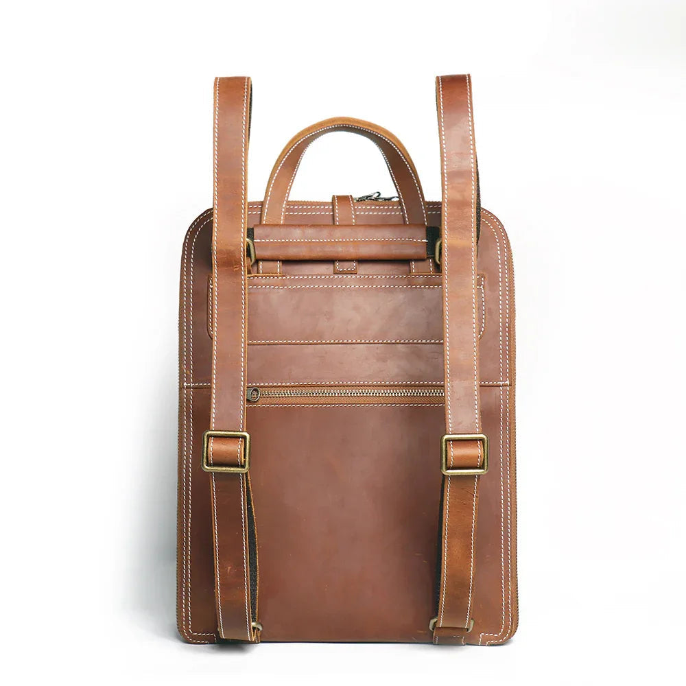 Small brown leather backpack with front zip pocket and dual buckle straps