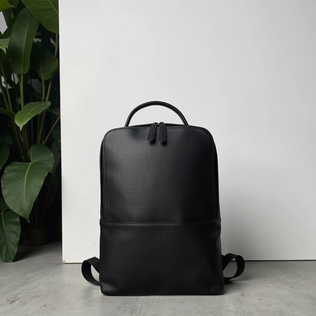 Black leather slim backpack with curved handle and adjustable shoulder straps