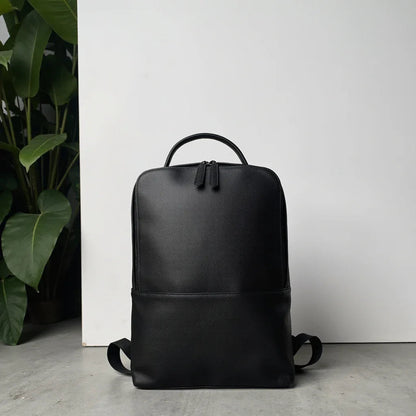 Black leather slim backpack with curved handle and adjustable shoulder straps