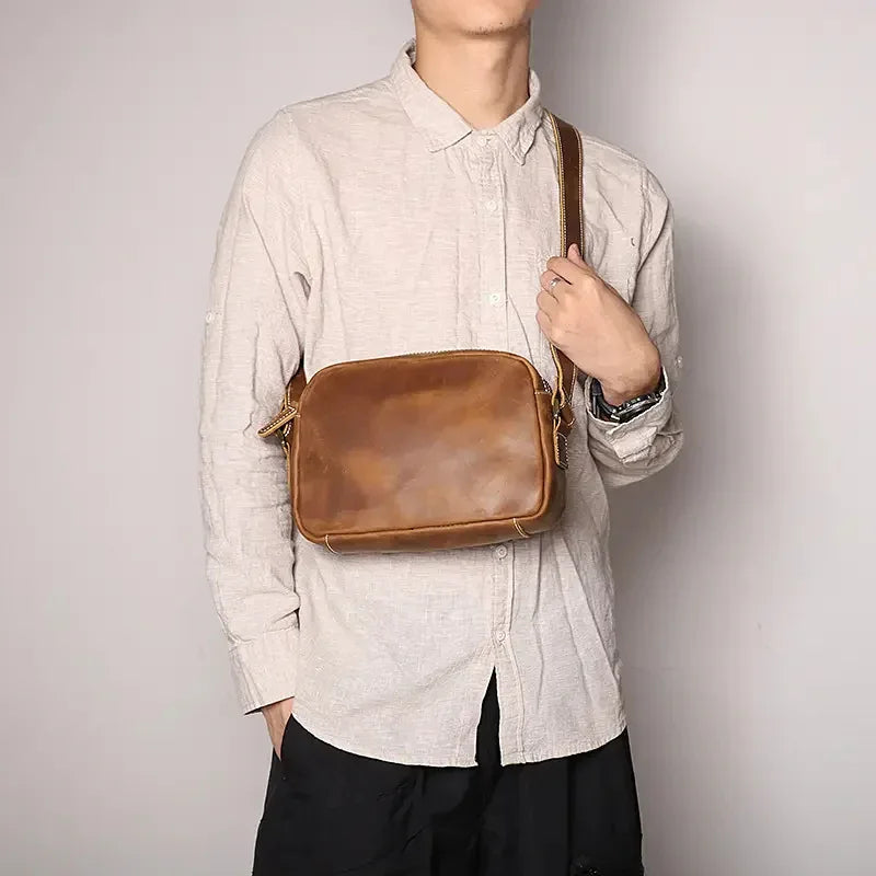 Brown leather crossbody bag worn on a chest with top zipper closure