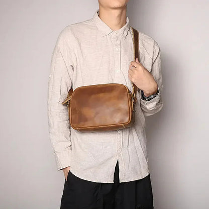 Brown leather crossbody bag worn on a chest with top zipper closure
