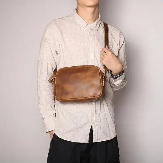 Brown leather crossbody bag worn on a chest with top zipper closure