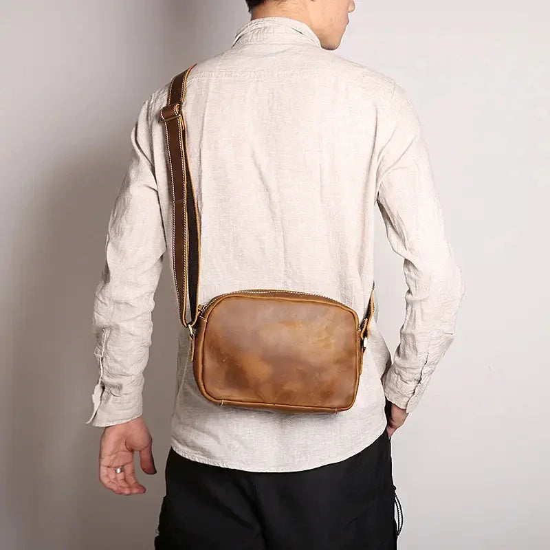 Brown leather crossbody bag worn across the back with adjustable strap