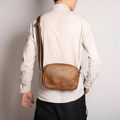 Brown leather crossbody bag worn across the back with adjustable strap