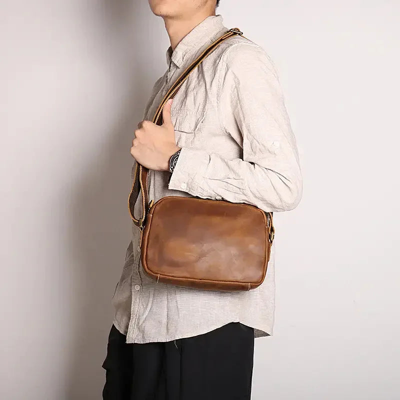Brown leather crossbody bag back side with shoulder strap and stitched detailing