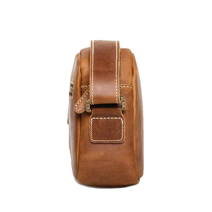 Brown leather crossbody bag side view with handle and small stitched patch